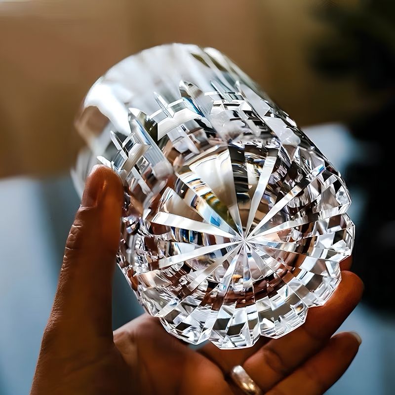 Hand turning a crystal whiskey glass over to show the starburst cut and scalloped base