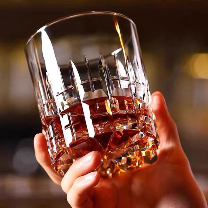 Hand holding a cut crystal rocks glass with a pour of whiskey