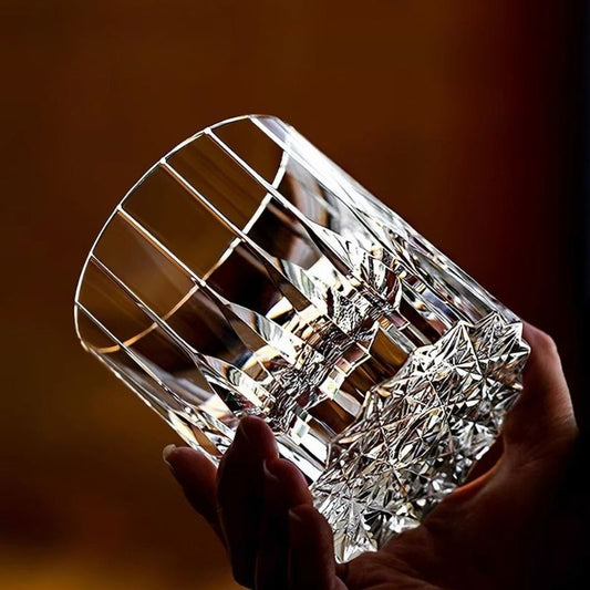 Hand holding a heavy hand-cut crystal whiskey glass against warm light