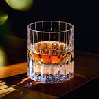 Crystal whiskey glass with whiskey on a dark wood bar top