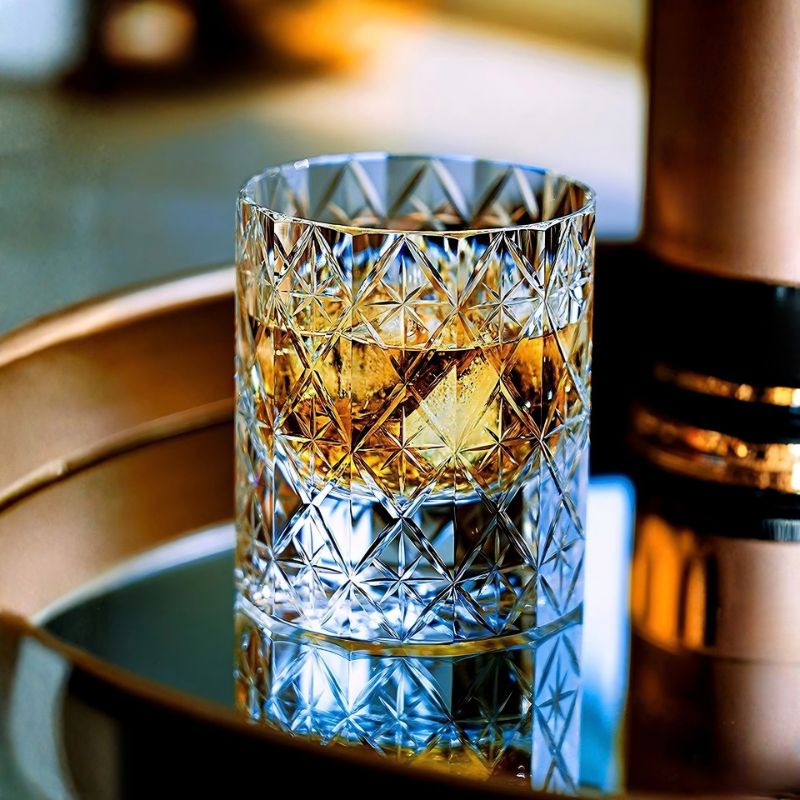 Polaris crystal rocks glass with whiskey and an ice cube on a mirrored bar tray