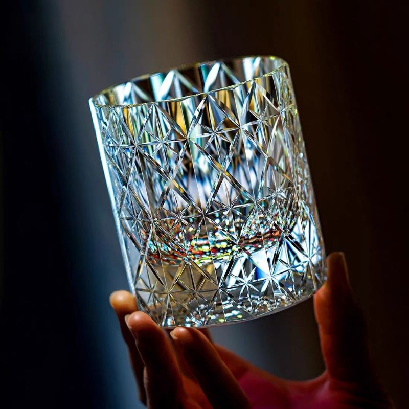 Empty Polaris crystal whiskey glass held to the light, showing the diamond lattice with a star cut in each panel