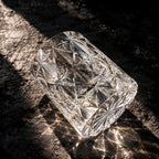Polaris cut crystal glass lying on dark stone, throwing light patterns across the surface