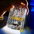 Hand tilting the Polaris hand-cut crystal whiskey glass with whiskey, showing the starburst cut on the base
