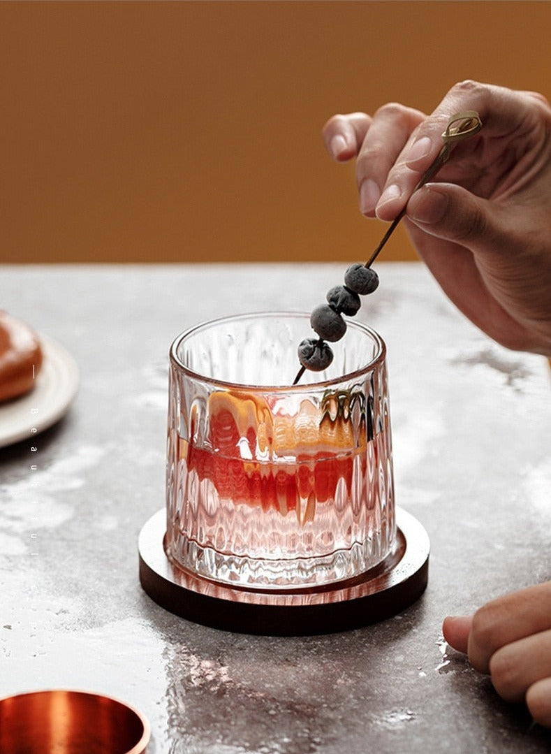 someone putting blueberries into a rotating whiskey glasses
