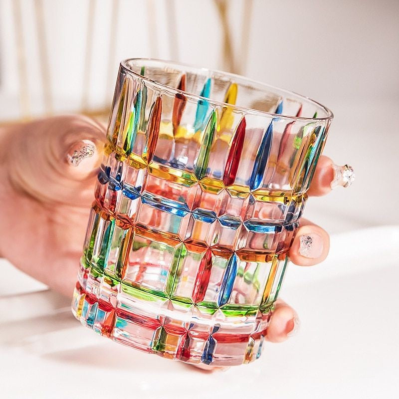 colorful whiskey glass holding by someone | Glasscias